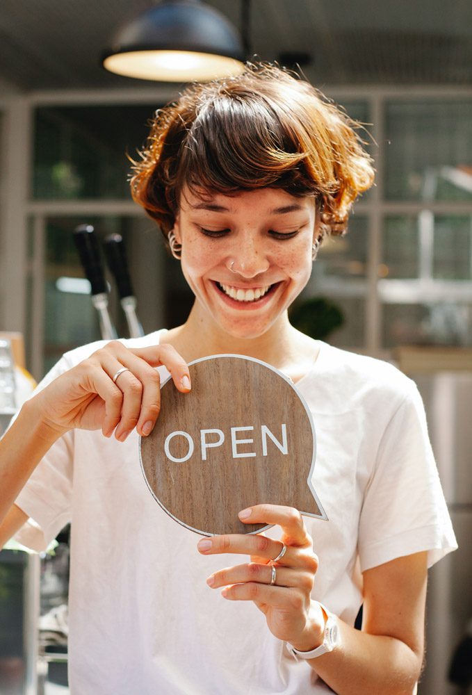 Woman holding an open sign for open method colonics